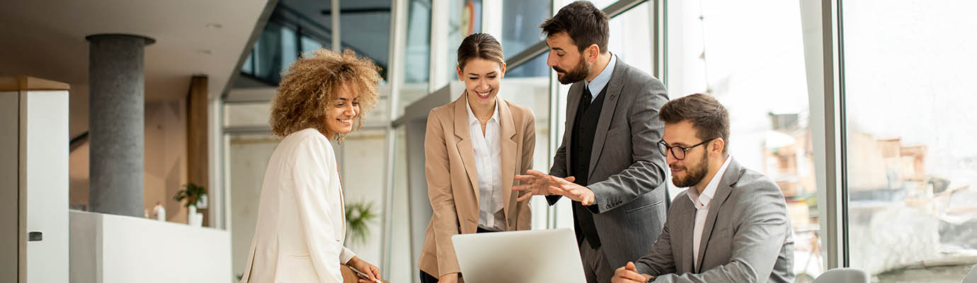 a group of colleagues sharing a laptop computer