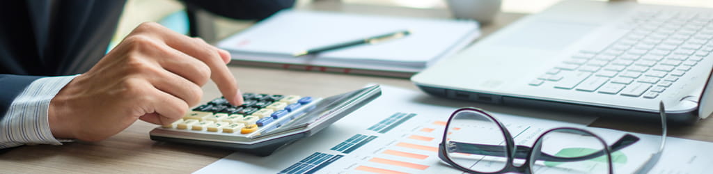 hand with a calculator and laptop illustrating tax