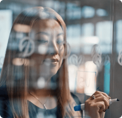 a woman writing on a glass wall
